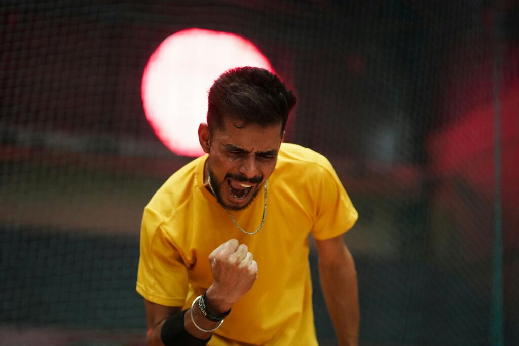pexels-photo-29873467-29873467 Man in yellow shirt celebrating a victory indoors with dramatic lighting.